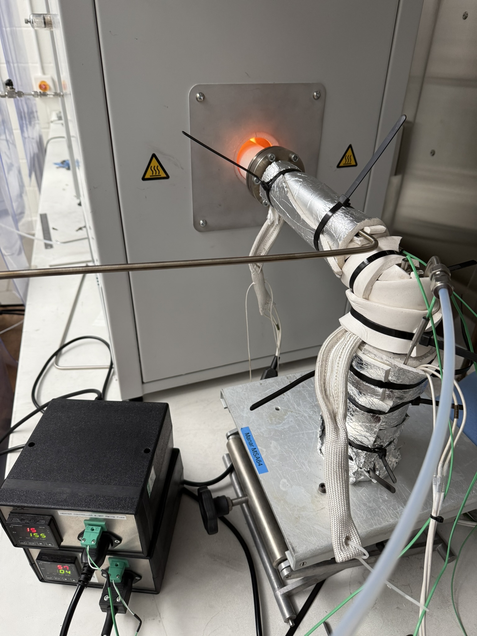 The insulated, heated sulfur delivery line clamped to the furnace flange, with two Omega PID controller boxes.